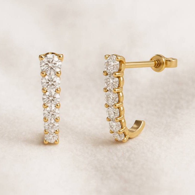 Gold hoop earrings with clear gemstones on a beige background