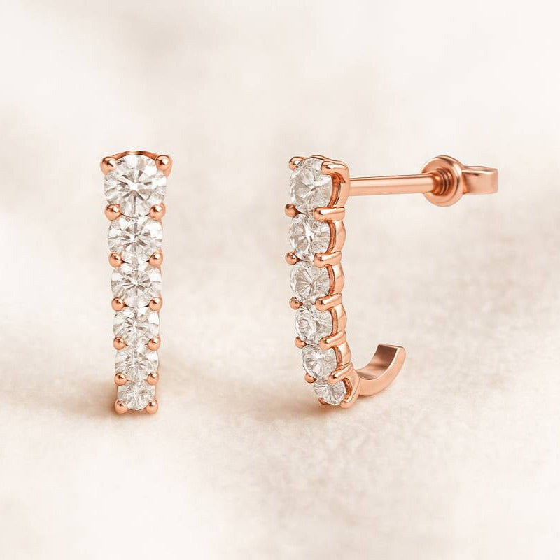 Rose gold hoop earrings with clear gemstones on a beige background